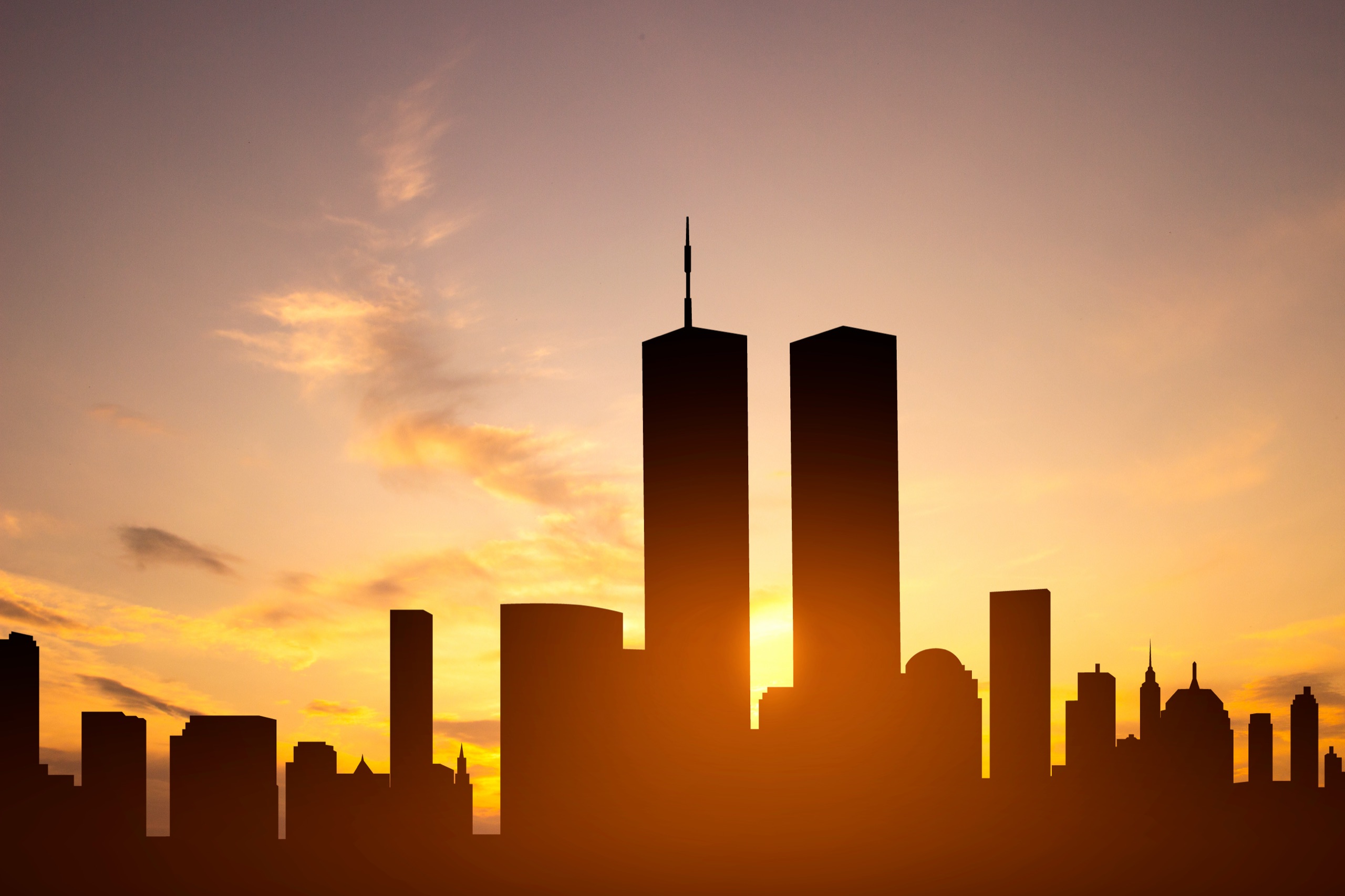 New York City skyline in silhouette at sunrise with the Twin Towers.