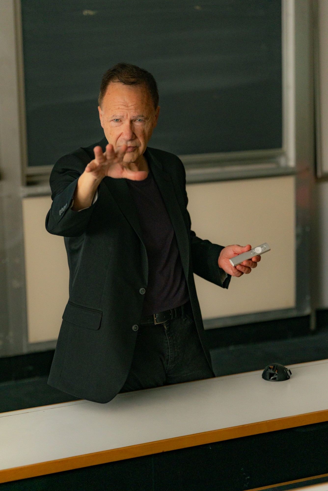 Chuck Garcia teaching in a lecture hall, reaching toward the camera with a presentation clicker in hand.